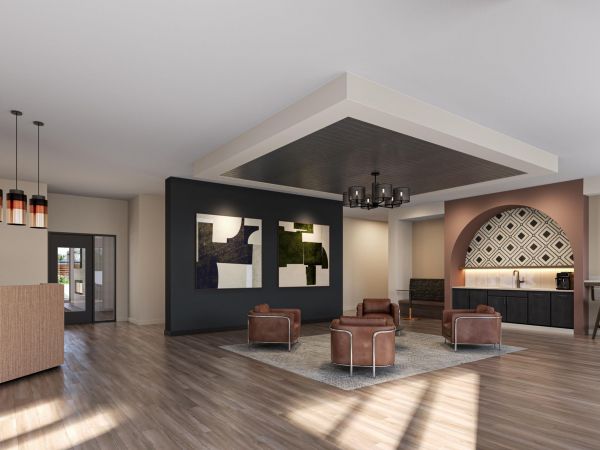 Modern lobby with brown leather chairs, abstract art on the wall, and a bar area with high stools.