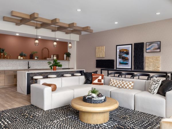 Modern living room with a white sectional sofa, round wood table, and open kitchen with bar stools and decor.