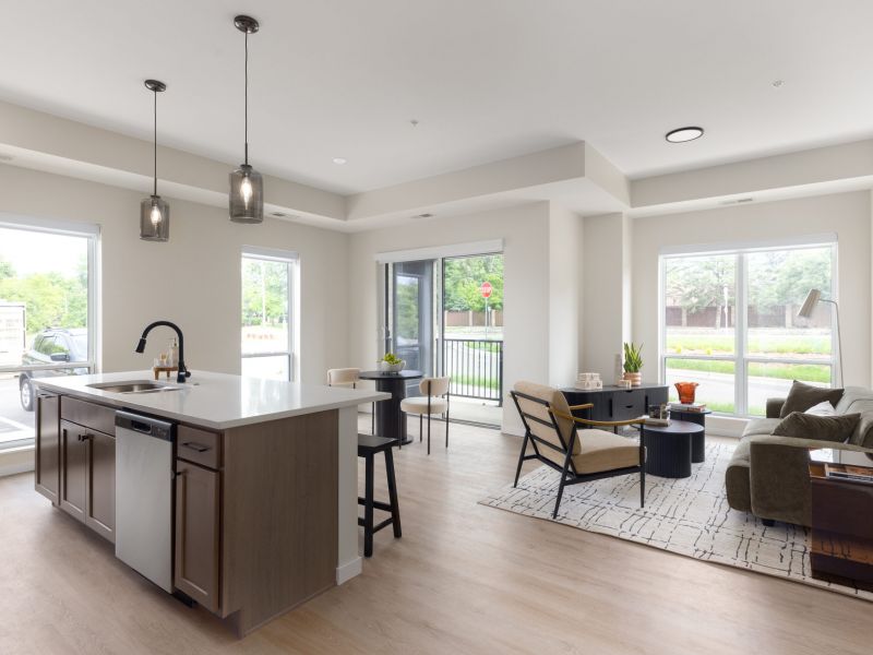 Modern open-plan kitchen and living room with large windows, neutral colors, and natural light.