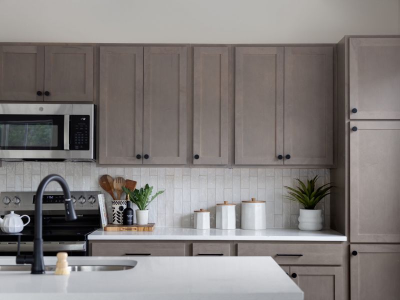 Modern kitchen with light wood cabinets, white countertop, and stainless steel appliances, including a microwave.