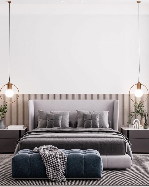 Modern bedroom with a gray bed, two pendant lights, nightstands, and a blue bench at the foot of the bed.