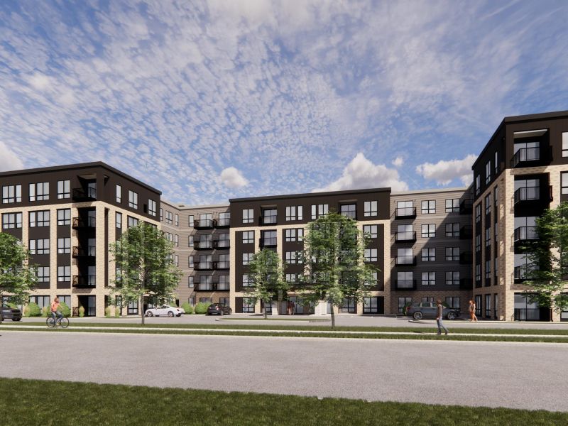 Modern apartment building with balconies, trees, cars, and people walking and biking under a partly cloudy sky.